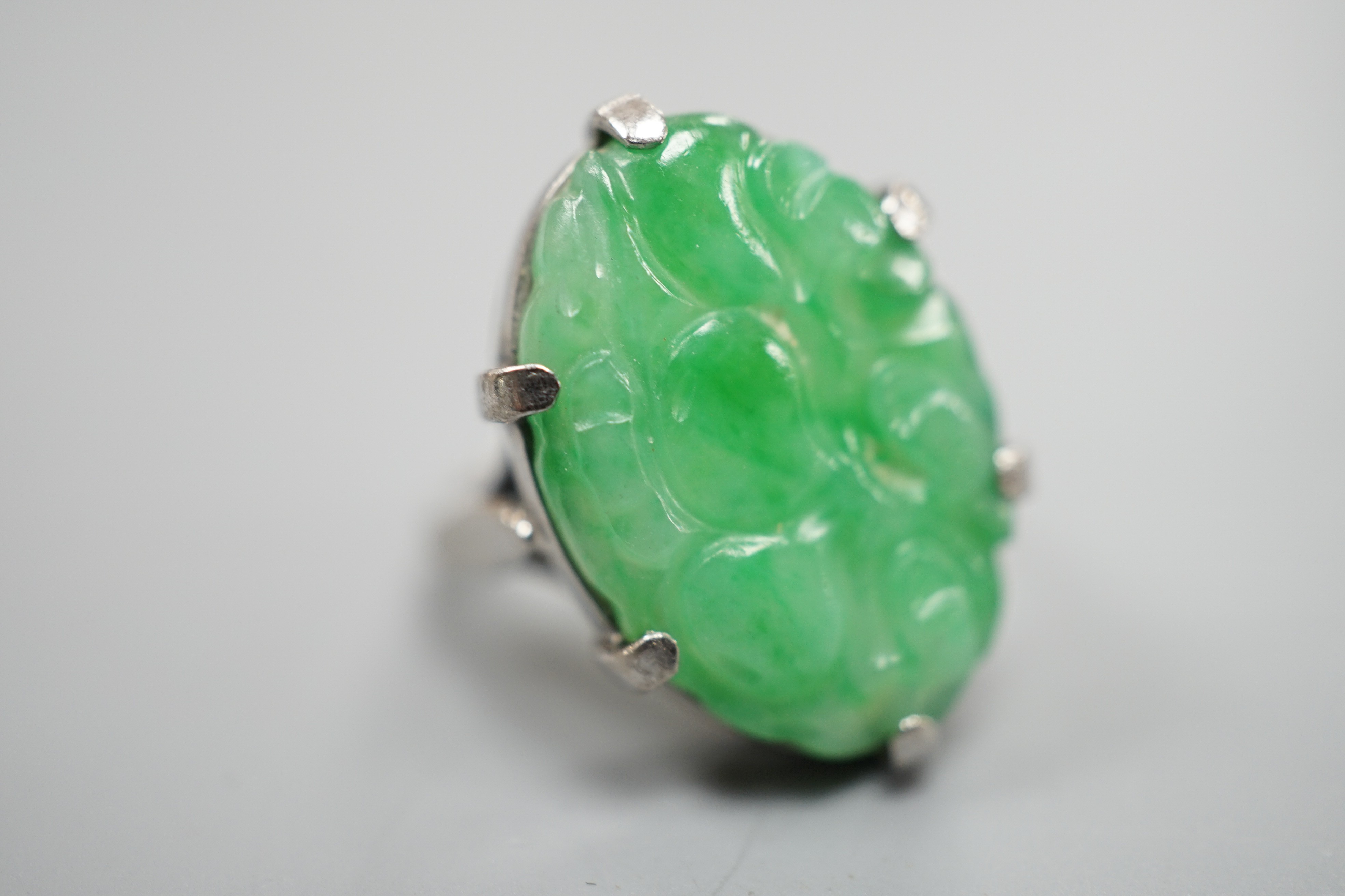 A white metal and oval jade set ring, carved with fruit, size F, gross weight 6.3 grams.